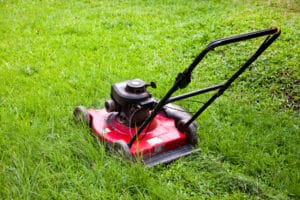 An old-school red lawnmower sitting in the grass