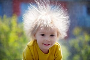 A cute boy with static electric hair smiling at the camera