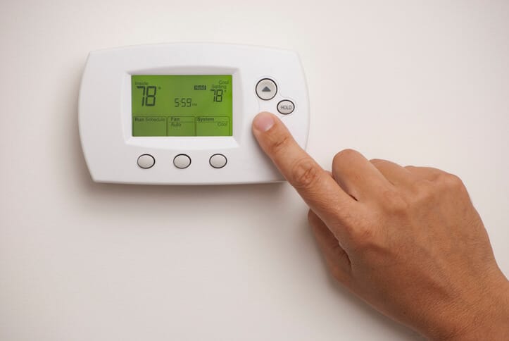 Digital Thermostat with a male hand, set to 78 degrees Fahrenheit.