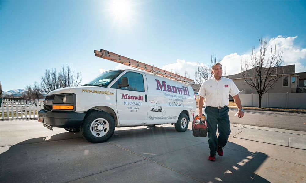 Manwill furnace repair man walks up driveway next to service vehicle