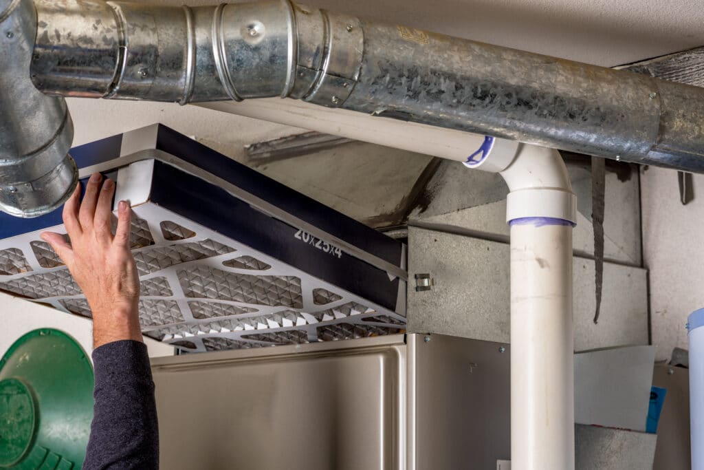 An HVAC professional replacing a heating system filter in preparation for the cold Utah winter