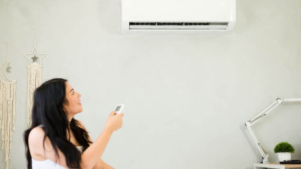 A woman turning on her ductless mini split system in a home office in Utah