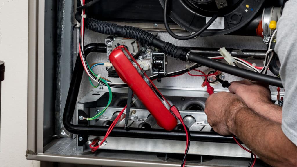 Manwill technician performing maintenance on a furnace heating system.