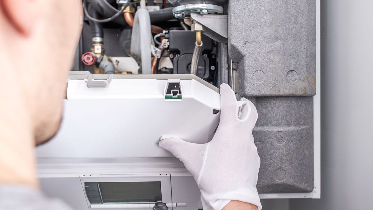 Technician servicing indoor HVAC equipment for heating and air conditioning repair