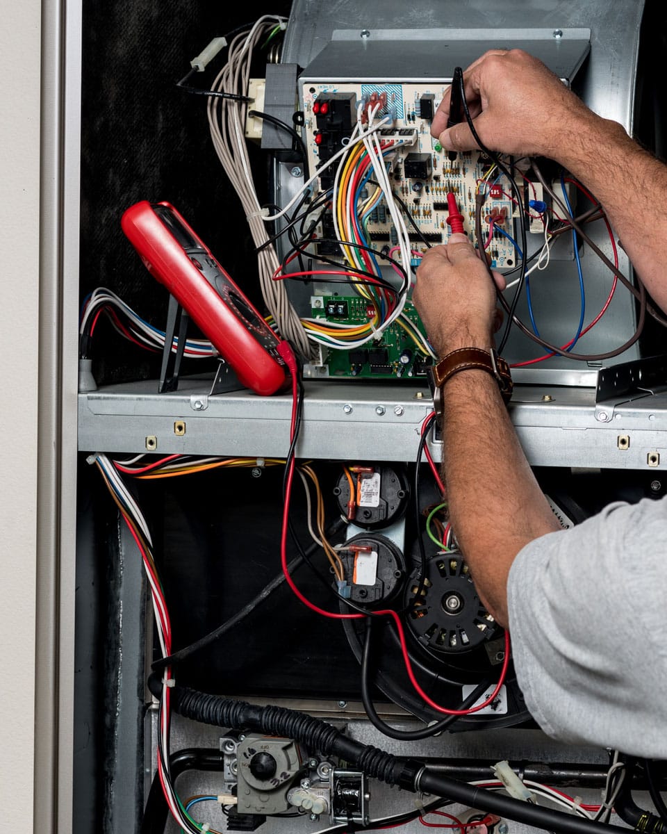 HVAC technician testing furnace wiring during heating repair service in Grantsville