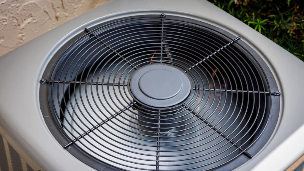 Close-up of the fan and grille on an outdoor air conditioning condenser unit.