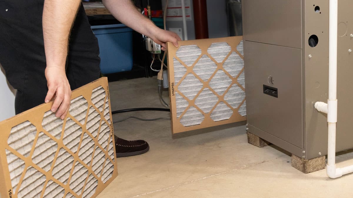 HVAC technician replacing a disposable furnace air filter during routine maintenance