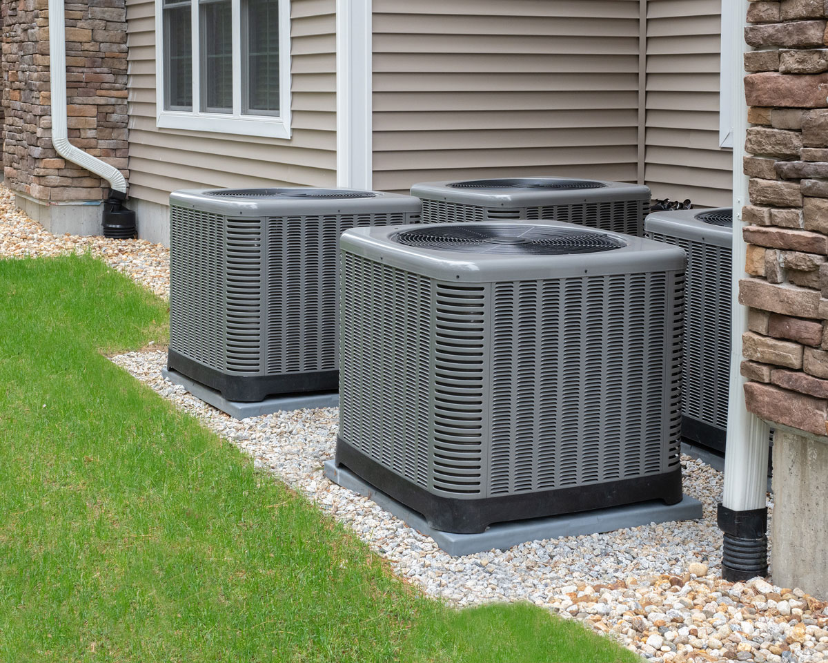 Multiple residential air-conditioning condenser units installed beside a home