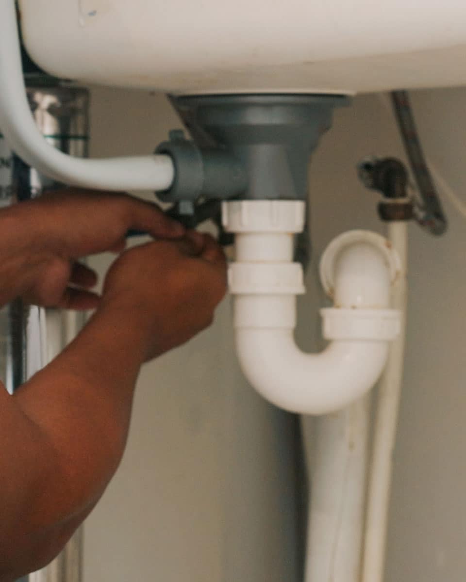 Plumber repairing the drainpipe and P-trap beneath a residential sink