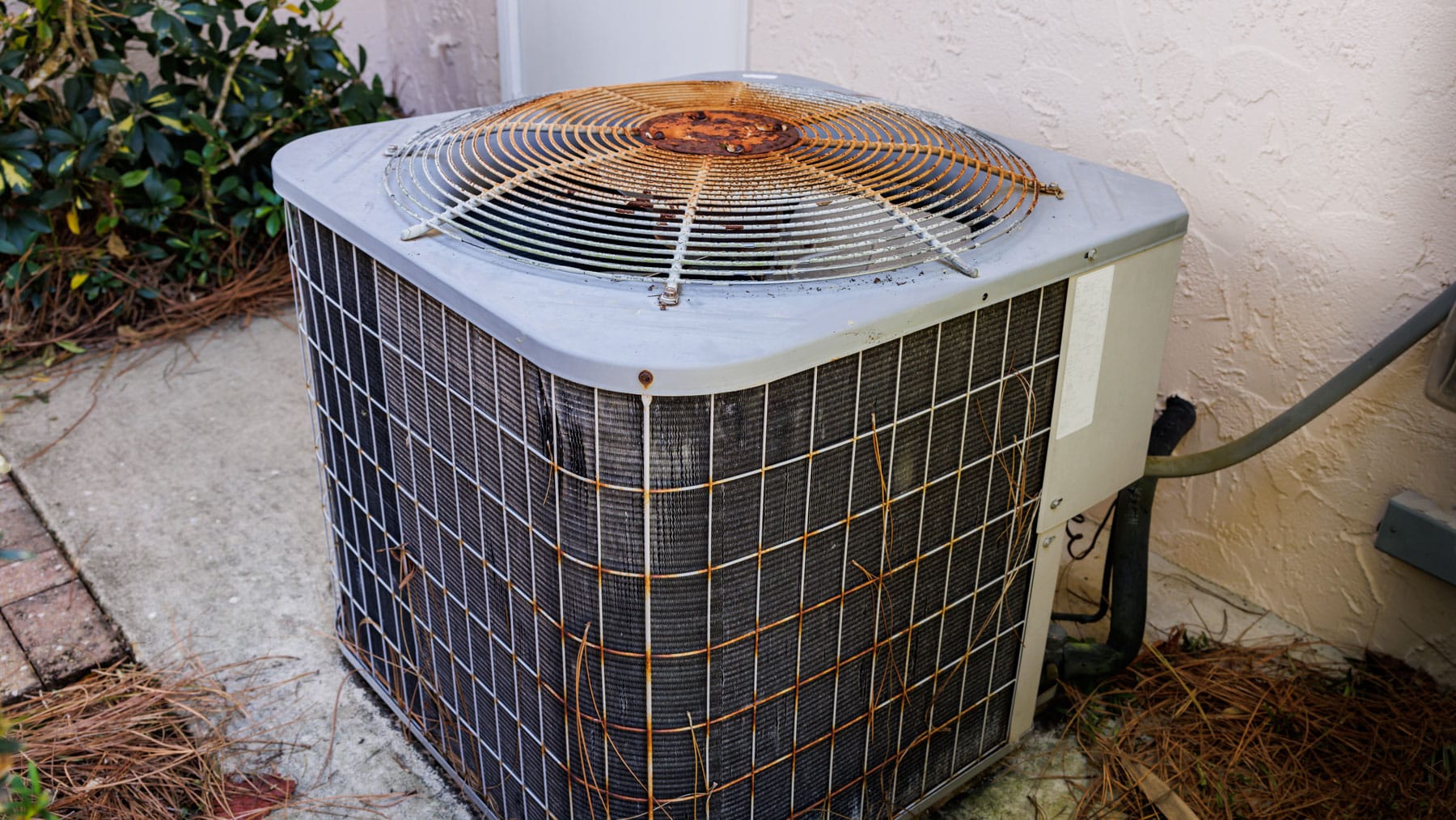 Older outdoor AC unit with visible rust and debris around the condenser fan.