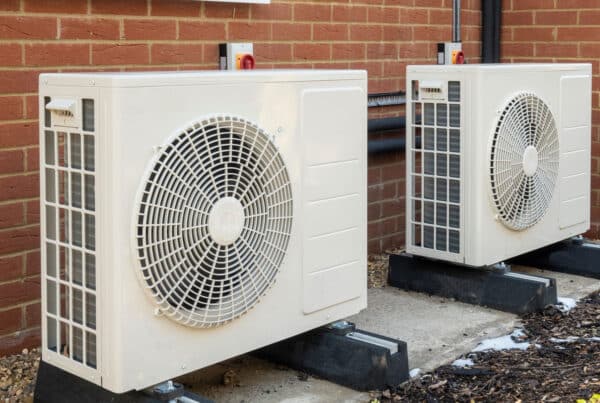 Two residential heat pump units installed outside a brick home