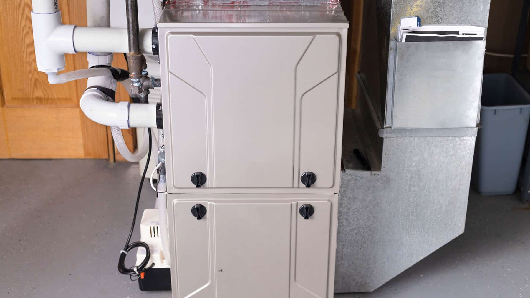Residential gas furnace connected to ductwork in a utility room.